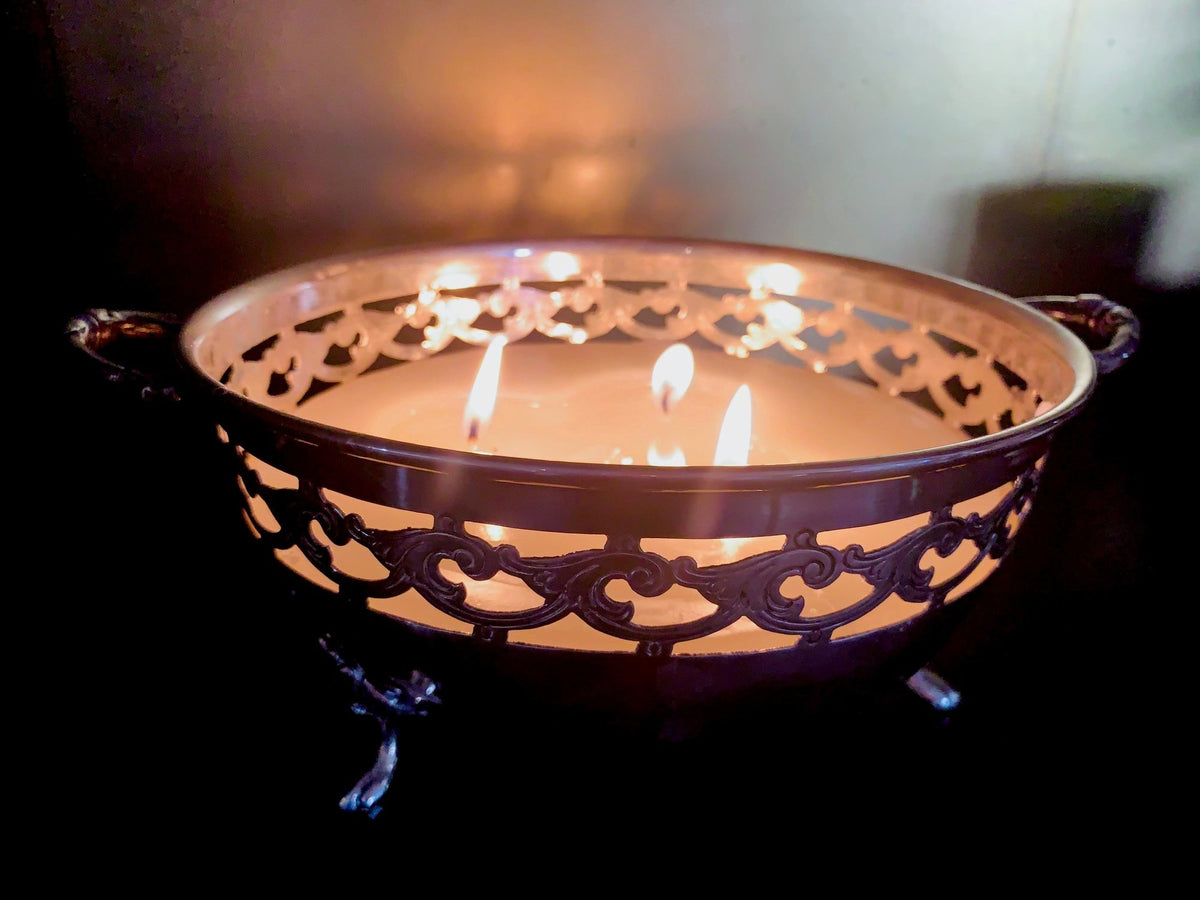 Lit candle in a pierced metal bowl