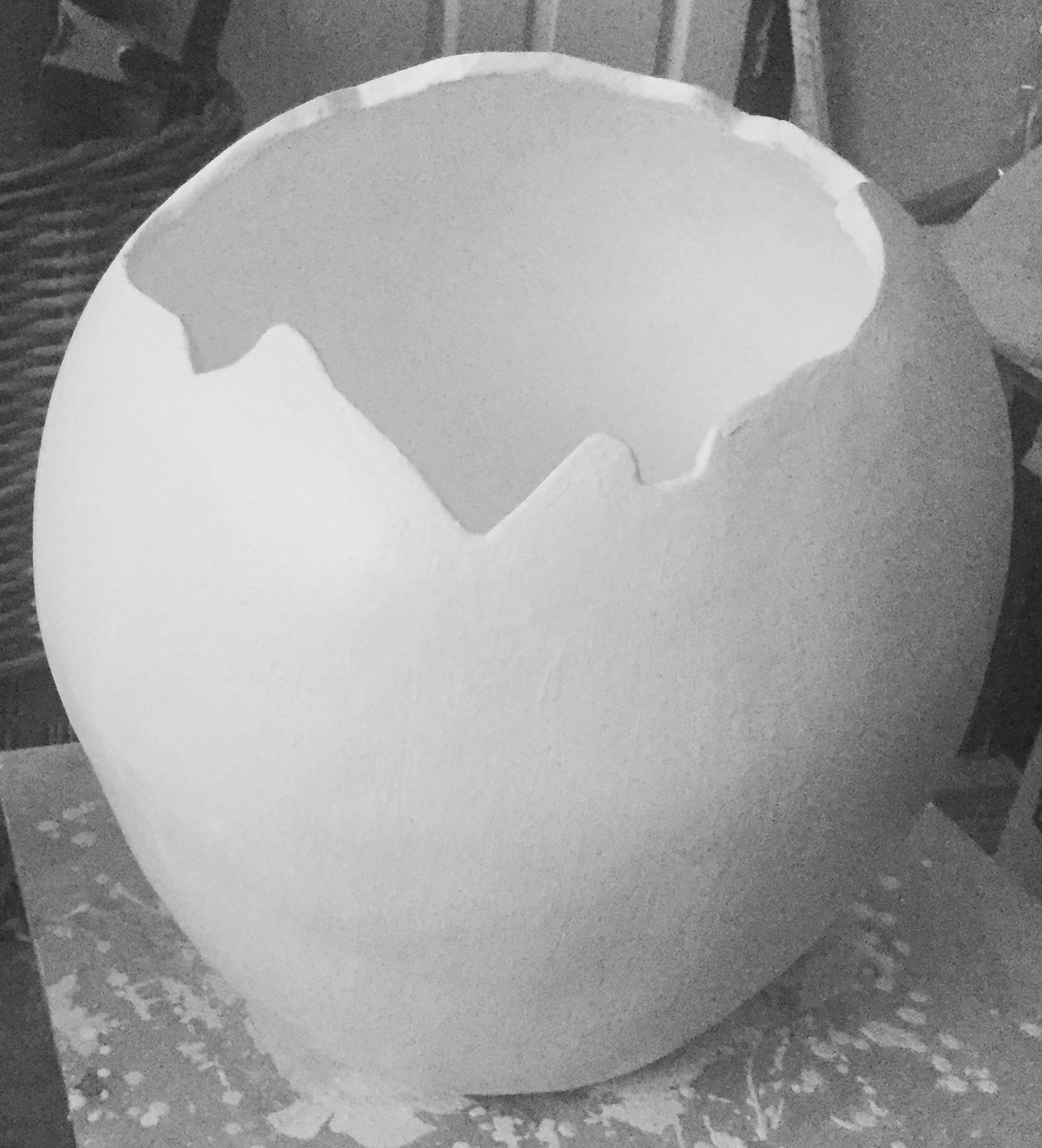 A white concrete pot with a broken eggshell rim