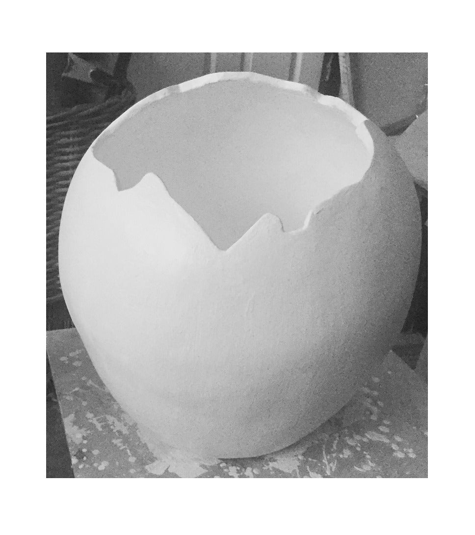 Eggshell urn, a round white cement pot with a broken rim