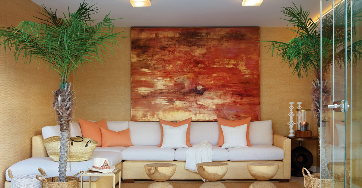 Ember Coast, a large red and gold abstract painting, above a white sofa on a covered terrace