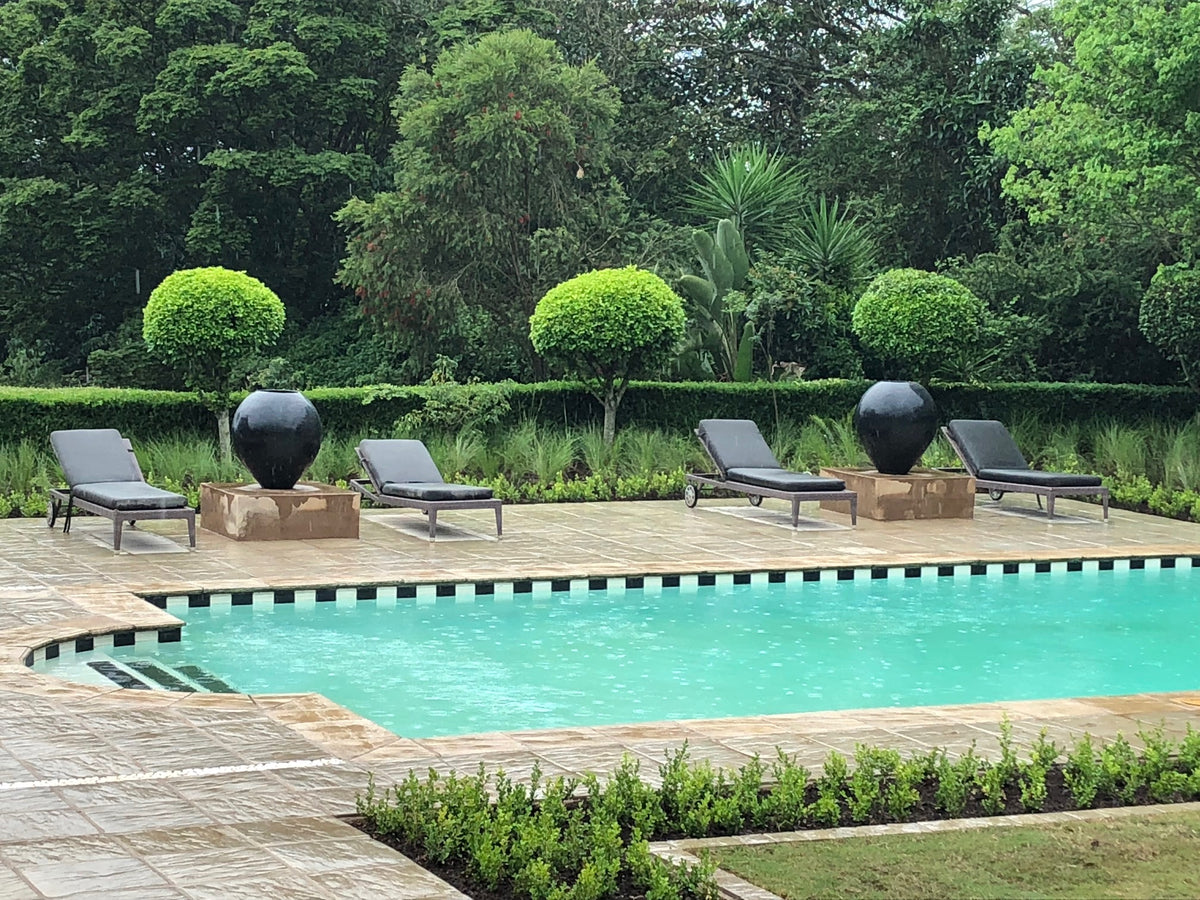 Two large black Omani pots on plinths beside a pool