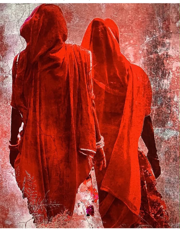 Two women in red saris walking away, photograph by Andrea Bowman