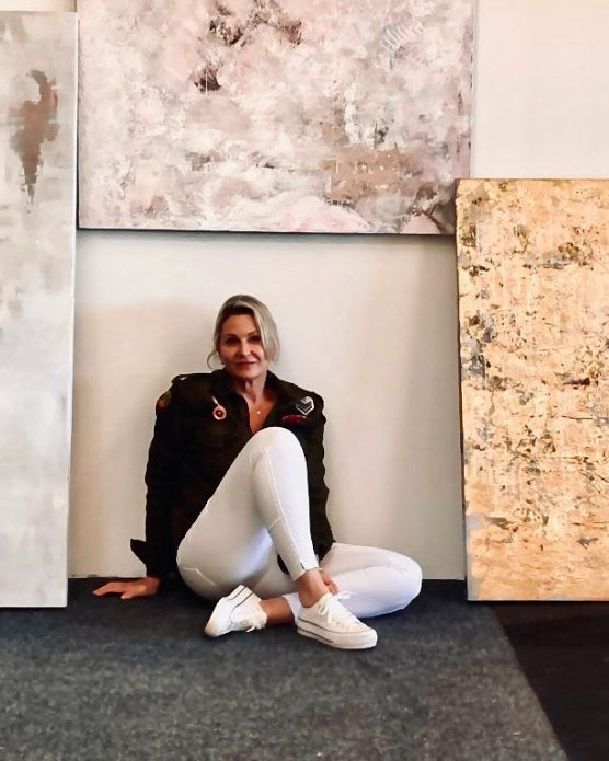 Andrea Bowman sitting on the studio floor among her canvases
