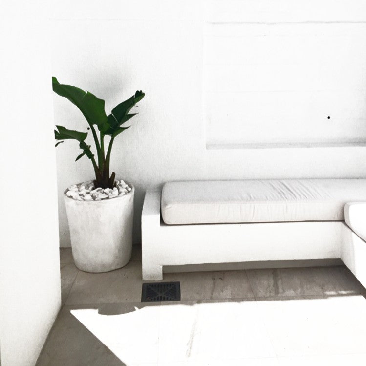 Tall white planter beside a white outdoor sofa