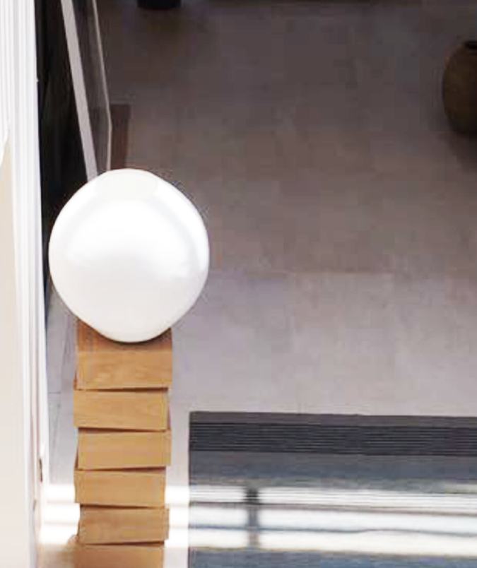 A smooth white sphere resting on stacked timber